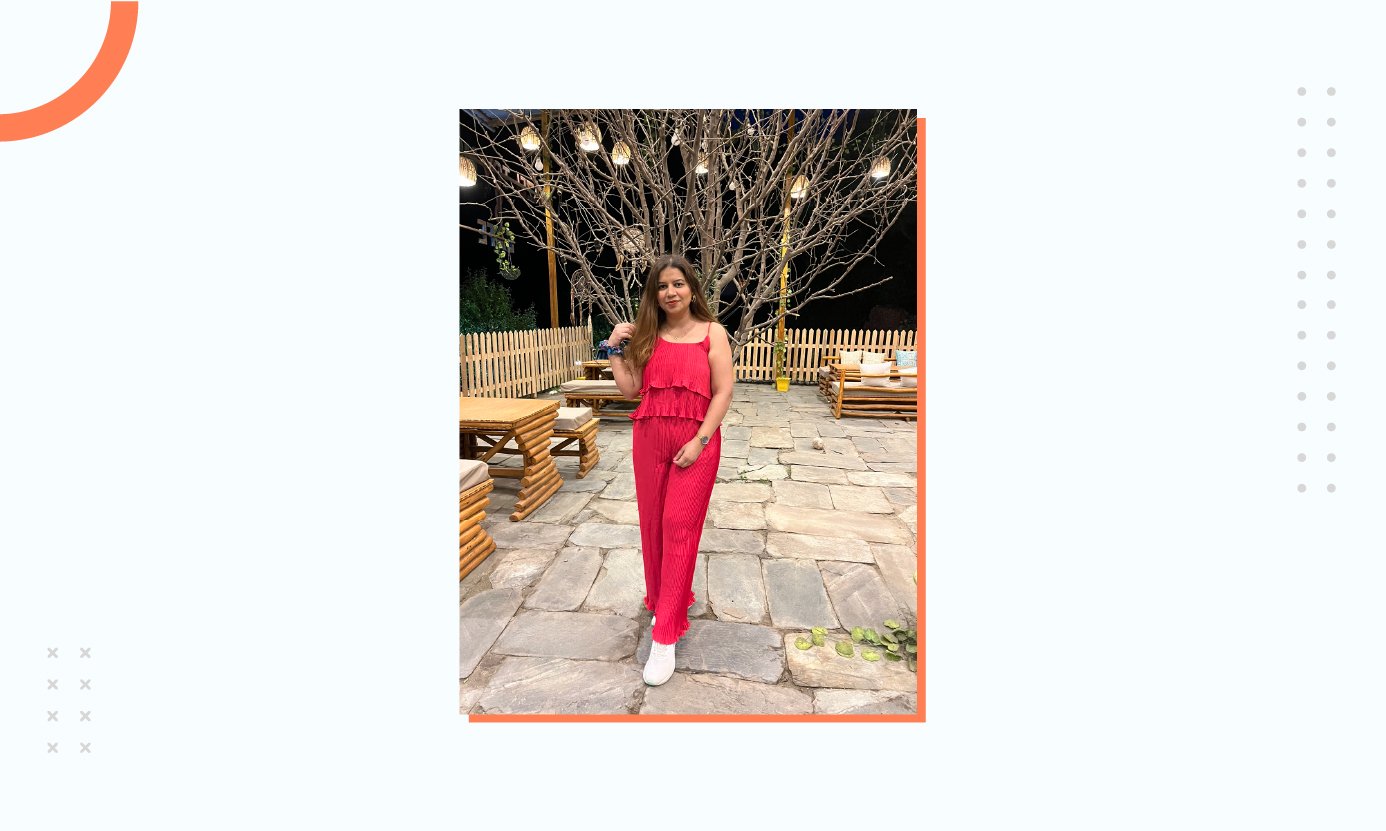 Arzoo Tomar standing in front of a lighted tree in red dress.