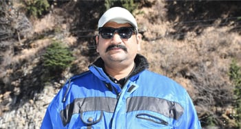 Axelerant DXP Consultant Abhishek Dhariwal posing for a picture in front of a mountain cliff